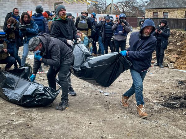 Працівники комунальної служби забирають тіла з місця злочину у Бучі, 5 квітня 2022 року. Фото: Тетяна Козак, Ґрати